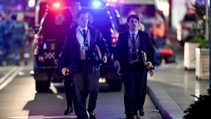 Deux policiers en civil marchent vers la caméra.