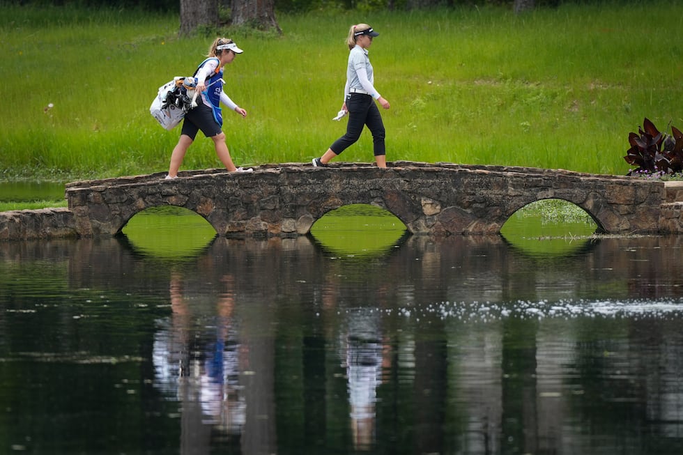 Brooke Henderson, of Canada, and her caddie walk over a bridge on the 15th hole during the...