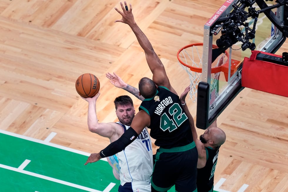 Dallas Mavericks guard Luka Doncic (77) looks to pass the ball while covered by Boston Celtics...