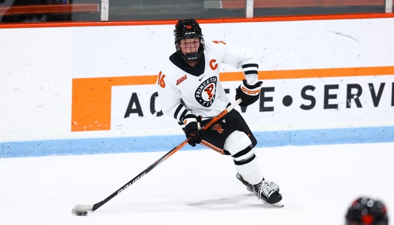 A female hockey player wearing a Princeton jersey carries the puck on the ice.