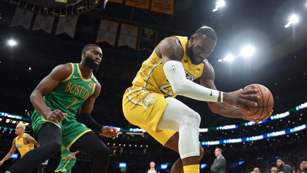 Jan 20, 2020; Boston, Massachusetts, USA;  Los Angeles Lakers forward LeBron James (23) saves the ball from going our of bounds ahead of Boston Celtics guard Jaylen Brown (7) during the first half at TD Garden. Mandatory Credit: Bob DeChiara-USA TODAY Sports