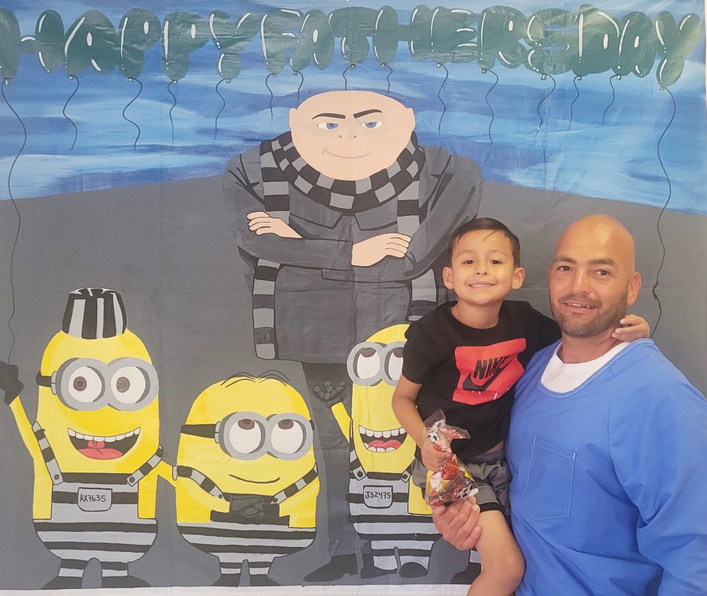 Gru and the Minions painted on a mural with an incarcerated fathers and his young child.