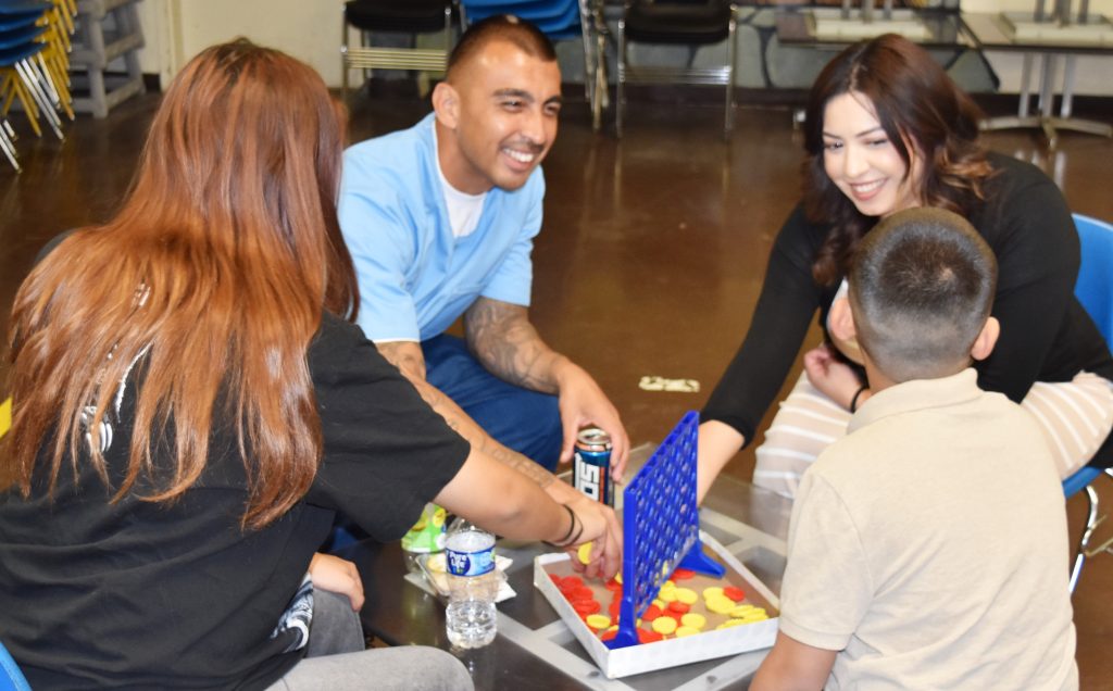 A visiting family plays a tabletop game with their incarcerated loved one.