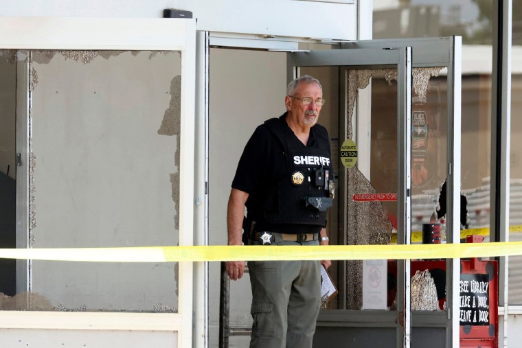 A A law enforcement officer stands at the entrance of the store