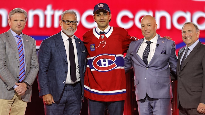 Il pose au centre des dirigeants de l'équipe.