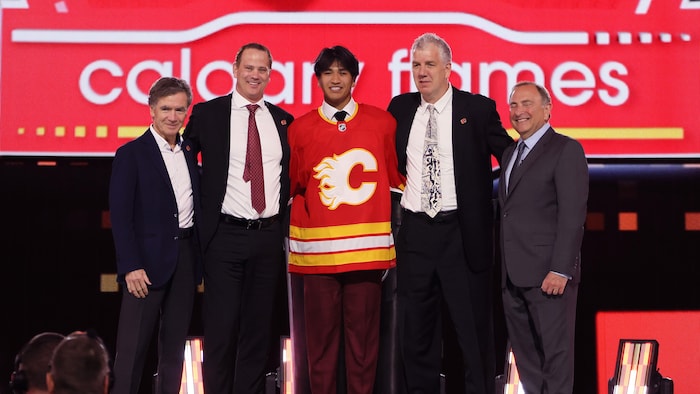 Zayne Parekh est debout sur scène et porte le chandail des Flames.