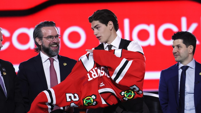 Sacha Boisvert enfile le chandail des Blackhawks de Chicago sur la scène du repêchage.