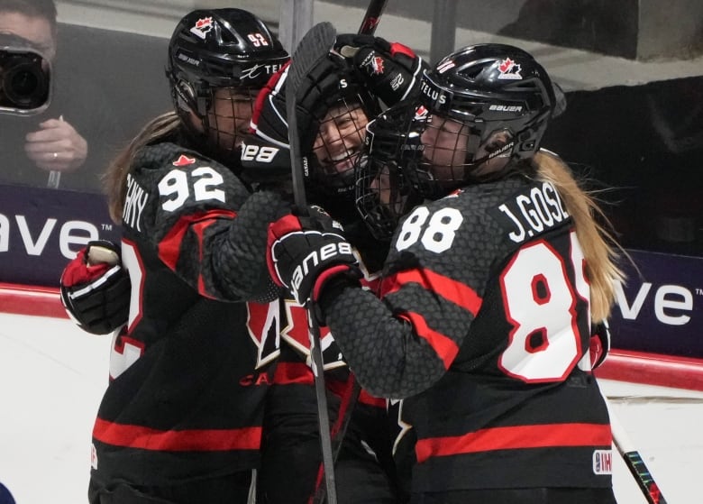 Three hockey players celebrate a goal.