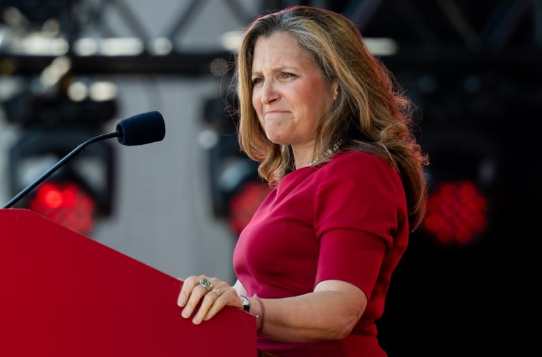 Minister of Finance and Deputy Prime Minister Chrystia Freeland wearing a red dress, standing at a red podium.