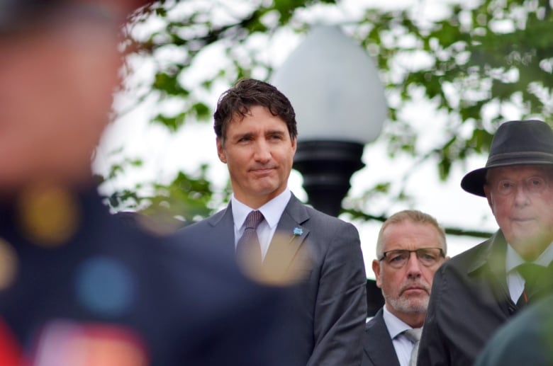 A man wearing a black suit standing among a crowd. 