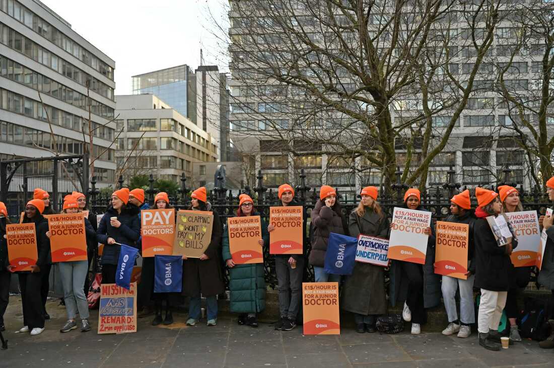 People hold British Medical Association branded placards calling for better pay on a picket line outside St. Thomas' Hospital in central London on Jan. 3, on the first day of a strike.