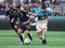 Vancouver Whitecaps' Andres Cubas, left, and Sporting Kansas City's Alan Pulido vie for the ball during the first half of an MLS soccer match, in Vancouver, on Wednesday, July 17, 2024.