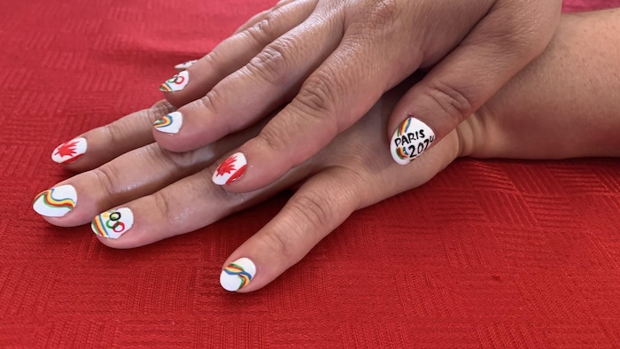 Gros plan sur les mains de Mélanie, avec des ongles peints aux couleurs du drapeau du Canada, du logo des jeux de Paris et des anneaux olympiques.