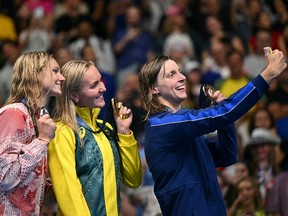 Silver medallist Canada's Summer Mcintosh (L), gold medallist Australia's Ariarne Titmus and bronze medallist US' Katie Ledecky takes a selfie with their medals on the podium.