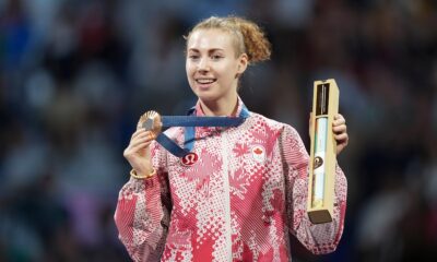 Eleanor Harvey poses with her medal and a box containing a poster on the podium