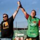 Competitive eater Joey Chestnut, right, celebrates after eating 13 olive burgers in five minutes before a minor league baseball game at Jackson Field in Lansing, Michigan on Aug. 10, 2023.