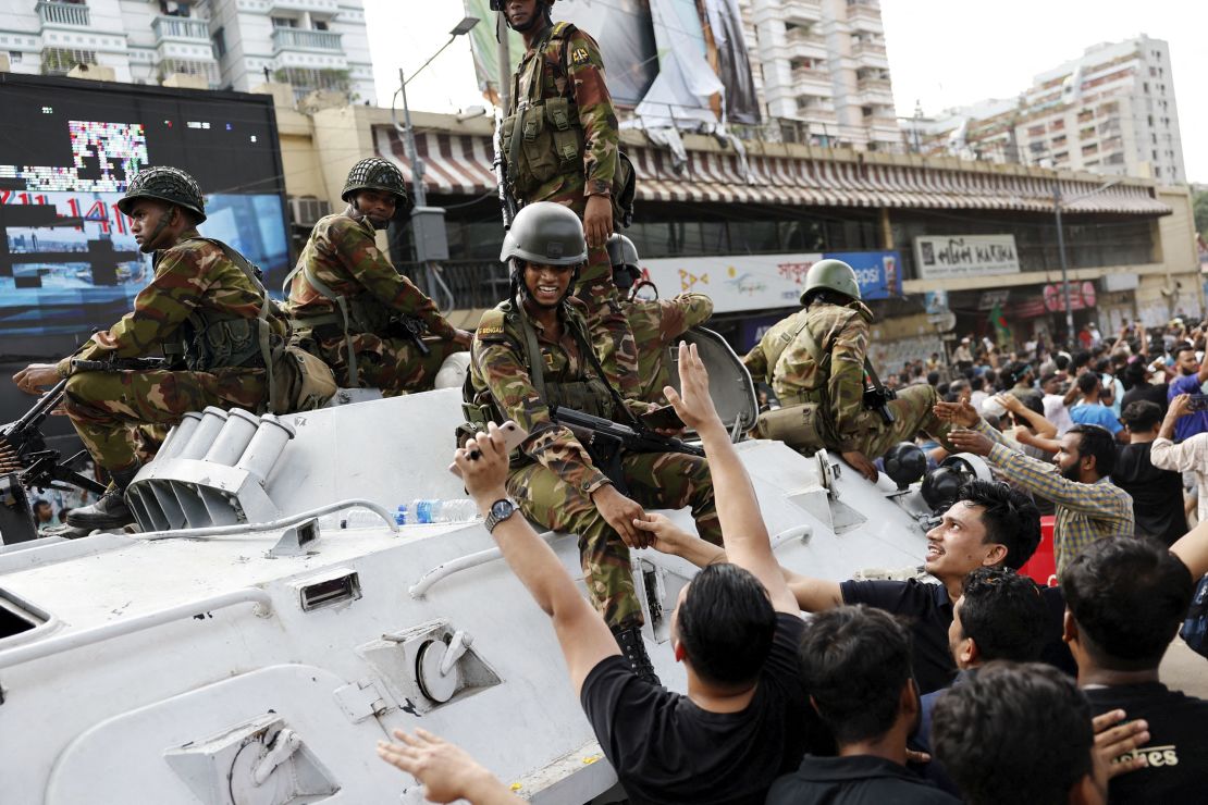 People shake hands with army personnel as they celebrate the resignation of Bangladeshi Prime Minister Sheikh Hasina in Dhaka on August 5, 2024.