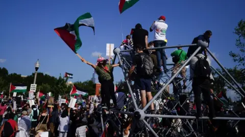 EPA A group of demonstrators waving Palestinian flags climb on a structure