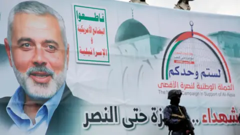 EPA A soldier stands next to a banner with a picture of Hamas political leader Ismail Haniyeh