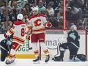 Calgary Flames right wing Adam Klapka, center, celebrates with defenseman Zayne Parekh, left, after scoring as Seattle Kraken goaltender Philipp Grubauer, right, looks on during the first period of a preseason NHL hockey game, Sunday, Sept. 22, 2024, in Seattle.