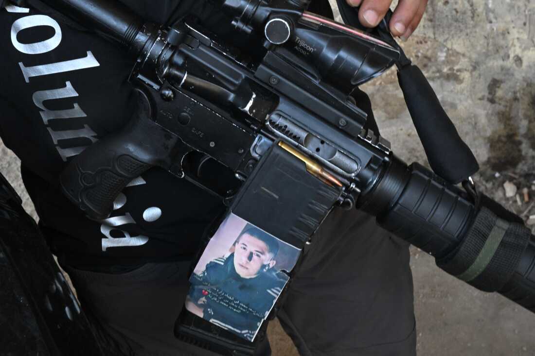 A Palestinian fighter in the occupied West Bank's Jenin refugee camp shares a photo of a Palestinian he says was killed by the Israeli military. He placed the man’s photo on his gun as a reminder.