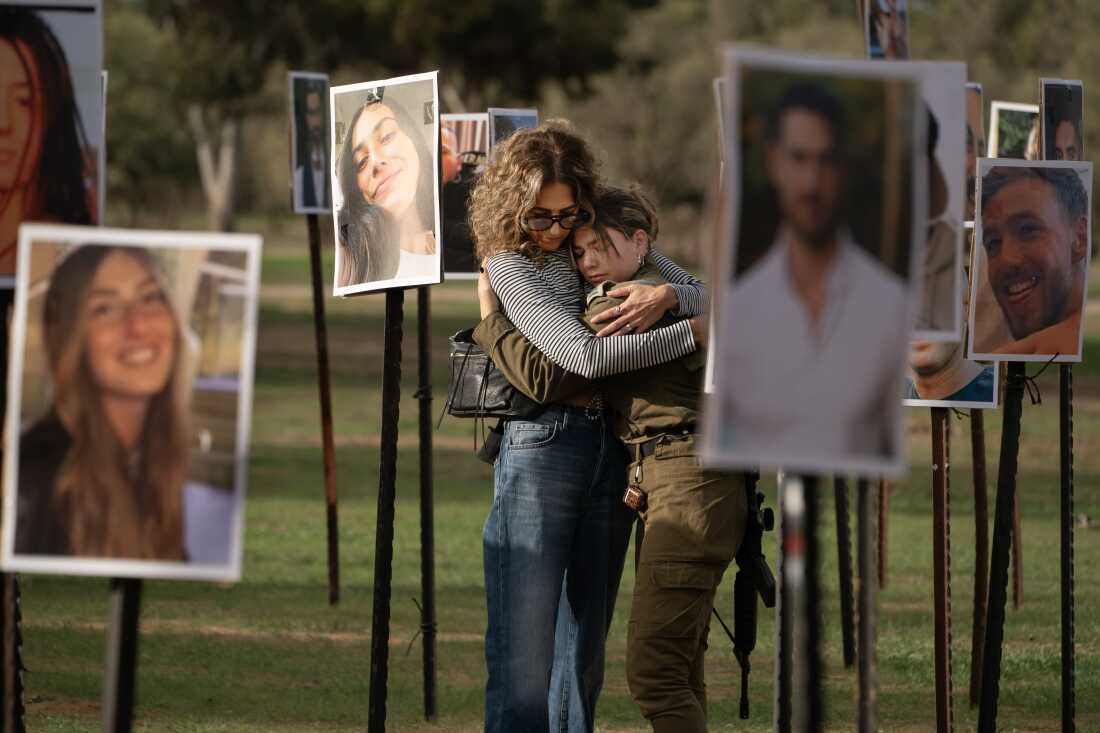 Sigal Manzuri embraces a friend of one of her daughters, Norelle, 25, and Roya, 22, who were killed on Oct. 7, 2023, when Hamas attacked the Nova music festival in southern Israel during a commemoration event at the site of the festival, on Nov. 28, 2023. Behind them are photos of people taken captive and killed by Hamas militants during their rampage through the festival.