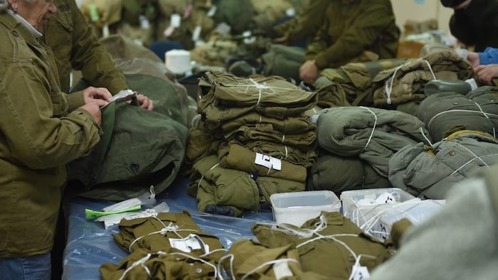 Des femmes plient des uniformes militaires.