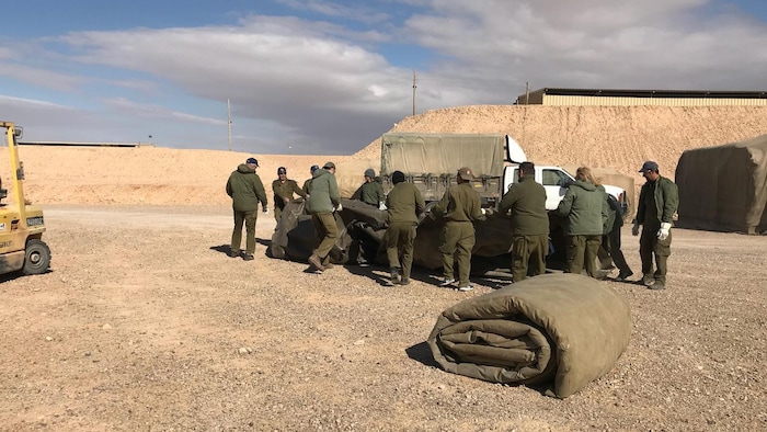 Des hommes et des femmes debout autour d'un véhicule militaire.