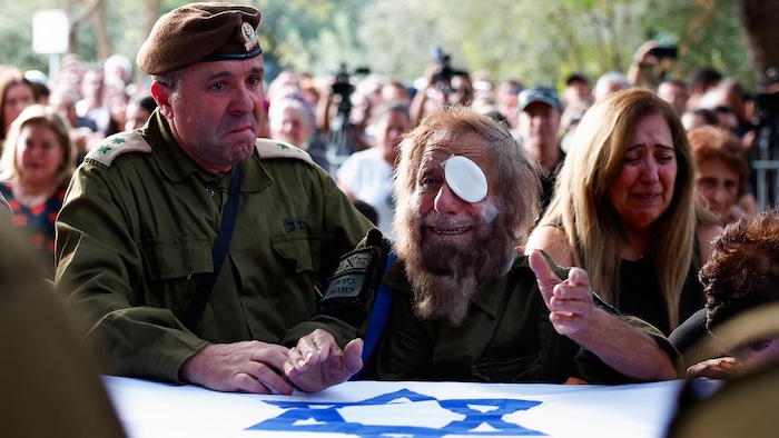 Des Israéliens, dont des militaires, pleurent devant un cercueil enveloppé du drapeau israélien.