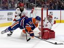 The Edmonton Oilers' Zach Hyman is hauled down by Carolina Hurricanes' Jalen Chatfield in front of goalie Frederik Andersen.