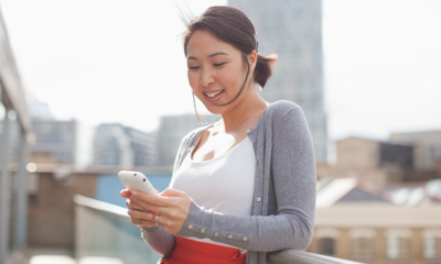 Smiling businesswoman text messaging with cell phone