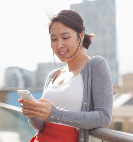 Smiling businesswoman text messaging with cell phone