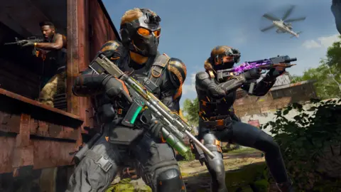 Microsoft Activision Blizzard A screengrab from the game showing three characters dressed in armour, holding assault rifles, surrounded by small buildings, grass and trees