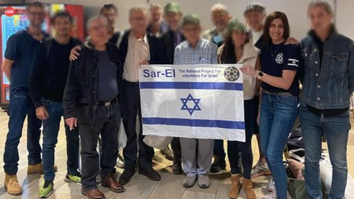 Plusieurs personnes posent en tenant un drapeau israélien.