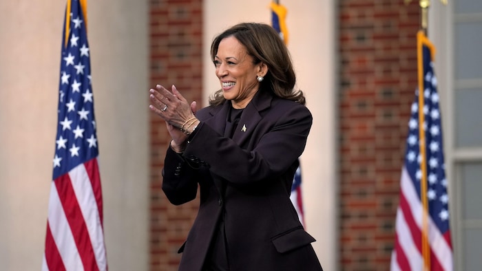 Kamala Harris sourit devant des drapeaux américains. 