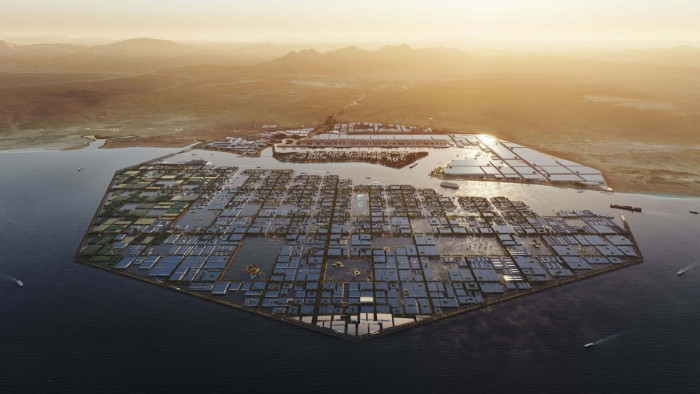 Aerial view of a futuristic, hexagonal water city with grid-like structures, surrounded by ocean and set against a desert landscape at sunset