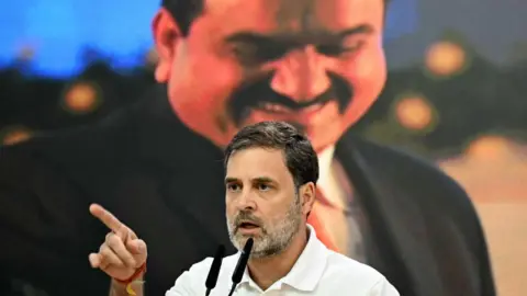 AFP India's Congress party leader Rahul Gandhi addresses a press conference against the backdrop of a picture of Indian industrialist Gautam Adani, at his party headquarters in New Delhi on November 21, 2024.