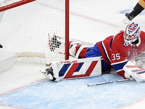 Hockey goalie sprawls and looks behind him as the puck goes into the net