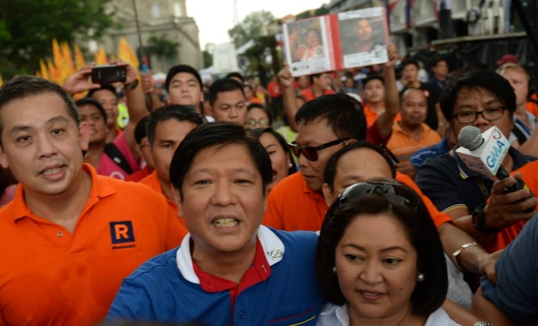 A person puts their arm around another as they navigate through a crowd.