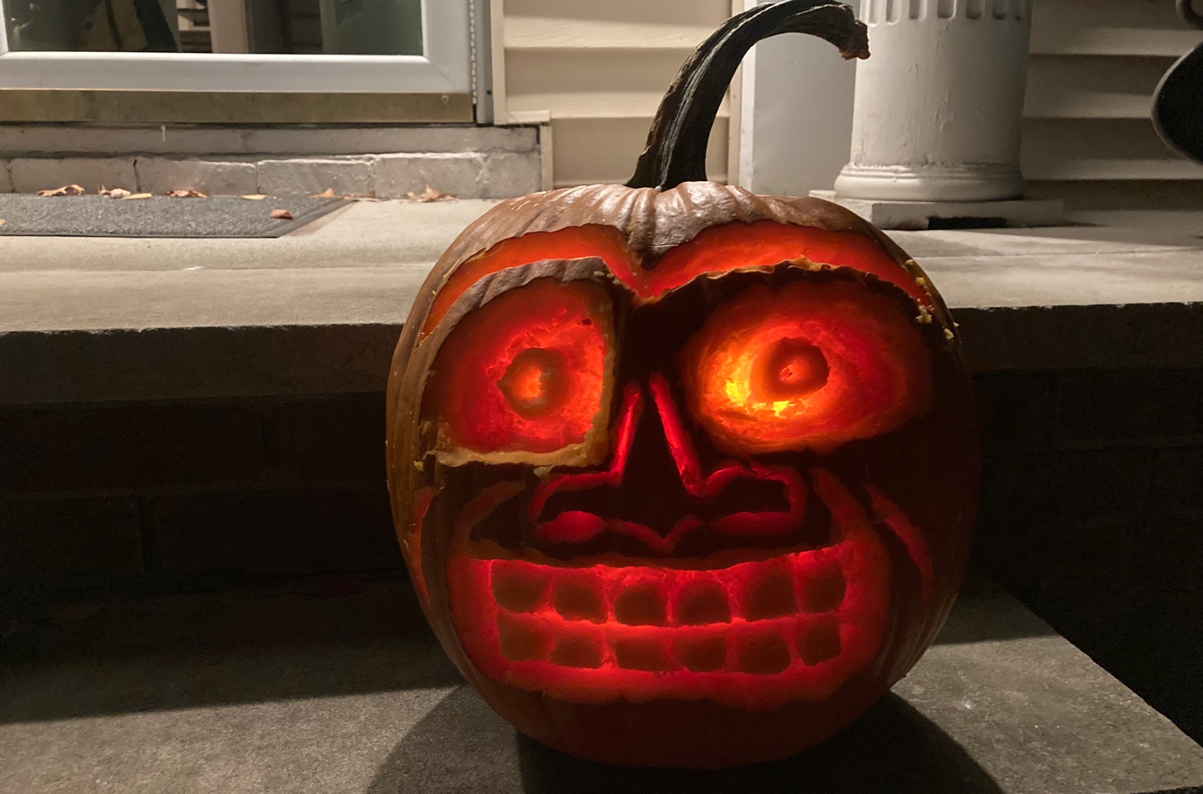 A jack-o-lantern with crazed eyes, a connecting unibrow, and a horrible grimace etched into its face. 