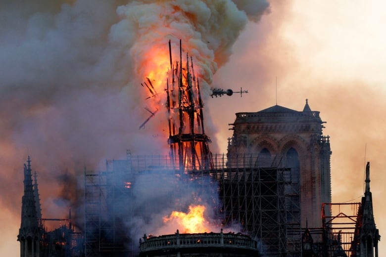 Fire and smoke engulfs a cathedral church's spire as it collapses.