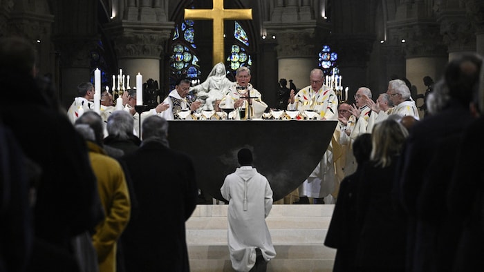 Un membre du clergé s'agenouille tandis que l'archevêque de Paris, Laurent Ulrich, dirige les prières pour la consécration du nouvel autel principal, œuvre de l'artiste et designer français Guillaume Bardet, qui remplace l'ancien, détruit en 2019, pendant une messe à la cathédrale Notre-Dame de Paris, à Paris, le 8 décembre 2024.