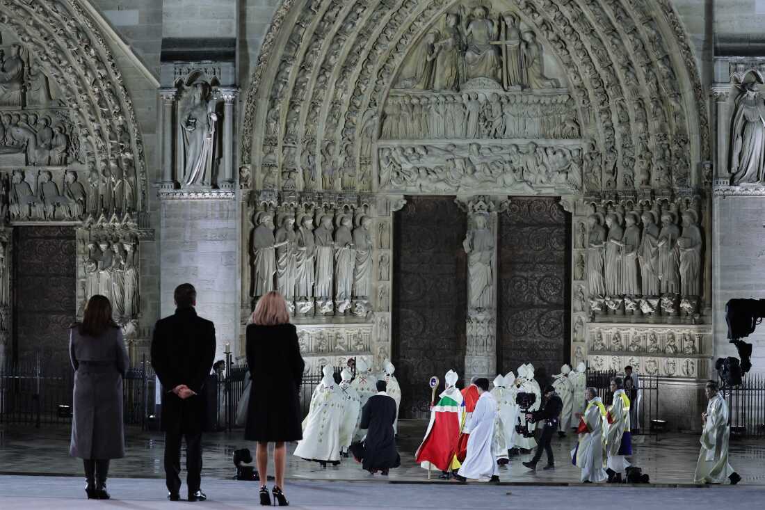 Mayor of Paris Anne Hidalgo (L), French President Emmanuel Macron (2L) and his wife Brigitte Macron (3R) stand as the Archbishop of Paris, Laurent Ulrich (C), walks to the doors of Notre-Dame Cathedral during a ceremony to mark the re-opening of the landmark Cathedral, in central Paris, on December 7, 2024. Around 50 heads of state and government are expected in the French capital to attend the ceremony marking the rebuilding of the Gothic masterpiece five years after the 2019 fire which ravaged the world heritage landmark and toppled its spire. Some 250 companies and hundreds of experts were part of the five-year restoration project at a cost of hundreds of millions of euros. (Photo by Christophe PETIT TESSON / POOL / AFP) (Photo by CHRISTOPHE PETIT TESSON/POOL/AFP via Getty Images)