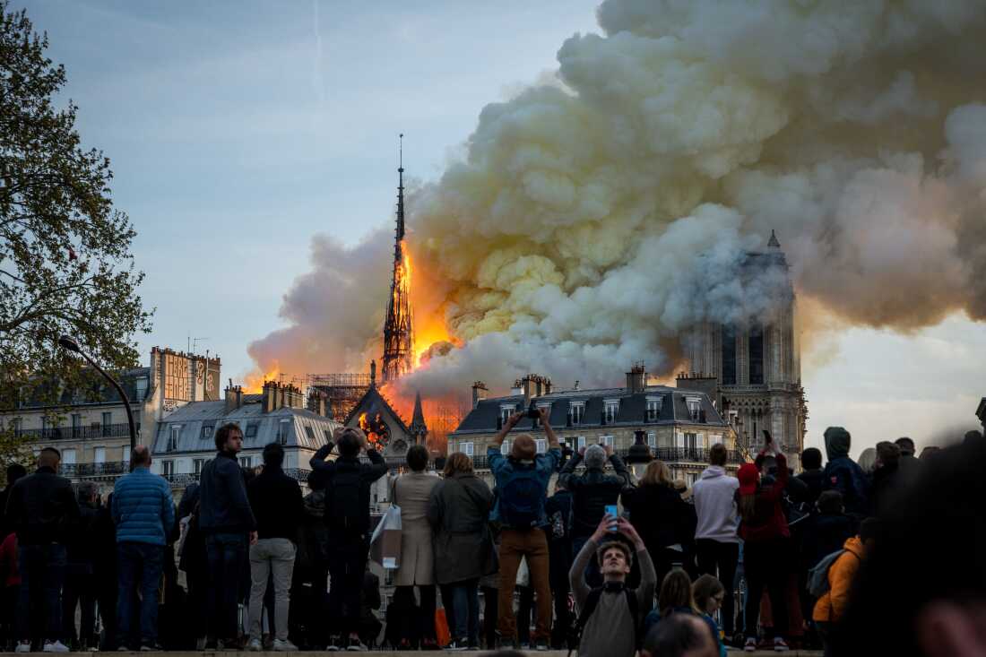 People watch the landmark Notre-Dame Cathedral burning in central Paris on April 15, 2019- A fire broke out at the landmark Notre-Dame Cathedral in central Paris, potentially involving renovation works being carried out at the site, the fire service said. (Photo by Nicolas Liponne/NurPhoto via Getty Images)