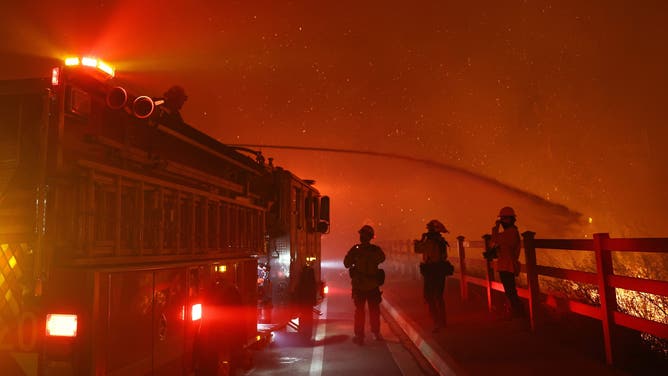 MALIBU, CALIFORNIA - DECEMBER 10: A firefighter sprays water as the Franklin Fire burns on December 10, 2024 on Malibu, California. The wildfire has scorched 1,800 acres near Pepperdine University prompting evacuations along the coast amid high winds with some structures destroyed. (Photo by Mario Tama/Getty Images)