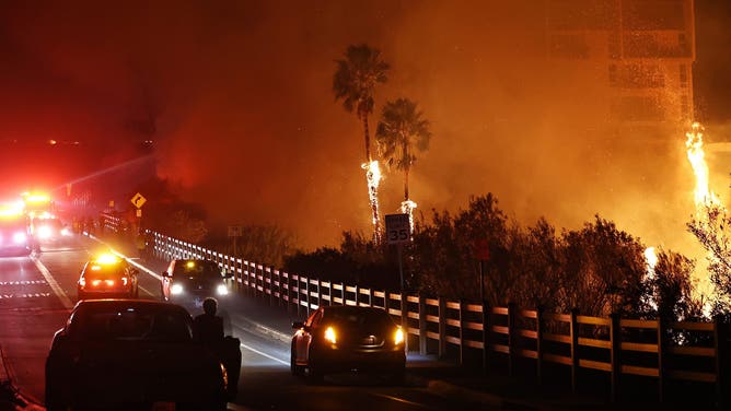 MALIBU, CALIFORNIA - DECEMBER 10: Firefighters work as the Franklin Fire burns near a building on December 10, 2024 in Malibu, California. The wildfire has scorched 1,800 acres near Pepperdine University prompting evacuations along the coast amid high winds with some structures destroyed. (Photo by Mario Tama/Getty Images)