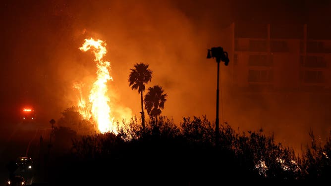 MALIBU, CALIFORNIA - DECEMBER 10: The Franklin Fire burns near a building on December 10, 2024 on Malibu, California. The wildfire has scorched 1,800 acres near Pepperdine University prompting evacuations along the coast amid high winds with some structures destroyed. (Photo by Mario Tama/Getty Images)