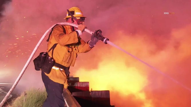 This image shows a firefighters working to beat back the flames of the Franklin Fire in Malibu outside Los Angeles.