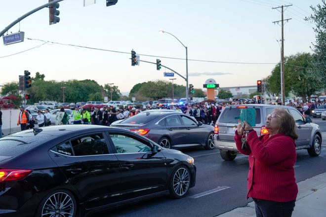 A bystander records participants walking in Virgen de Guadalupe pilgrimage through the Coachella Valley as it moves through Indio, Calif., Dec. 12, 2024.