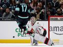 Jaden Schwartz of the Seattle Kraken jumps over the puck as Linus Ullmark of the Ottawa Senators makes a save.